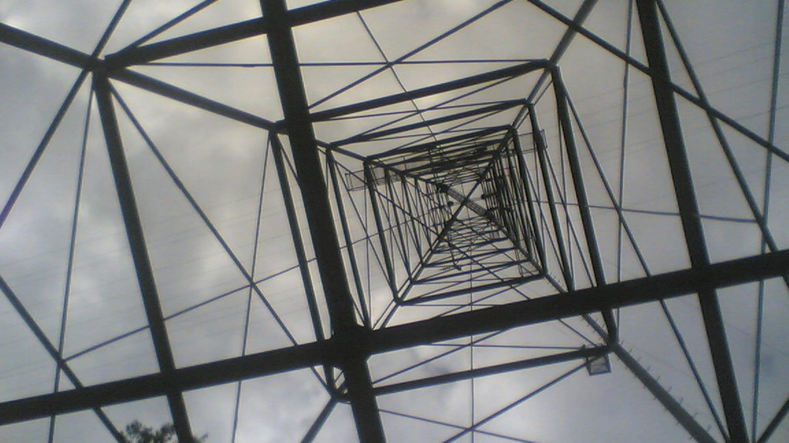 Stahlgittermast einer Hochspannungsleitung von unten fotografiert